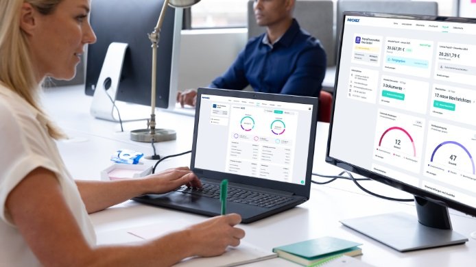 Lohnabrechnung selbst machen - Eine Mitarbeiterin der Lohnbuchhaltung arbeitet am Schreibtisch mit der Lohnabrechnungssoftware von Paychex Europe