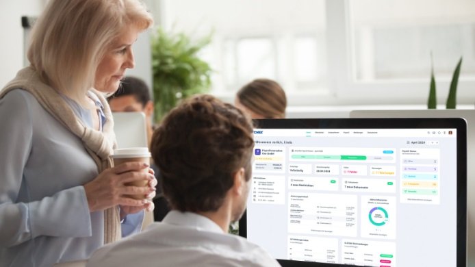 Lohnabrechnung selbst machen - Zwei Payroll-Kollegen betrachten gemeinsam einen Bildschirm mit Lohnabrechnungssoftware von Paychex Europe