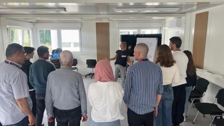 Die ROTE NASEN Humortrainerin Maria Gundolf präsentiert den Teilnehmenden in einem der regelmäßigen Humorworkshops in der Ankunfts- und Notunterbringungseinrichtung für Geflüchtete in Berlin-Tegel die unterschiedlichen Arten des Humors. // Weiterer Text über ots und www.presseportal.de/nr/116383 / Die Verwendung dieses Bildes für redaktionelle Zwecke ist unter Beachtung aller mitgeteilten Nutzungsbedingungen zulässig und dann auch honorarfrei. Veröffentlichung ausschließlich mit Bildrechte-Hinweis. Quelle: ROTE NASEN Deutschland e.V.