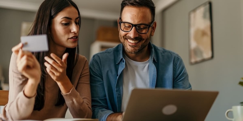 Paar nutzt Laptop und hält eine Barclays Visa Kreditkarte für Online-Einkauf AB