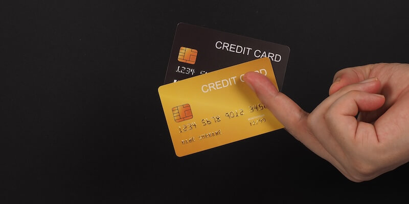 Hand mit zwei Kreditkarten vor schwarzem Hintergrund – Instabank Kreditkarte vs. Bank Norwegian Kreditkarte im Vergleich AB