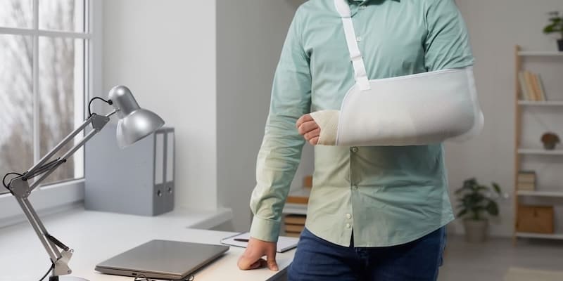 Selbstständige Person mit eingegipstem Arm im Büro – Symbolbild für Arbeitsausfall und Bedeutung der BU-Versicherung für Selbstständige AB